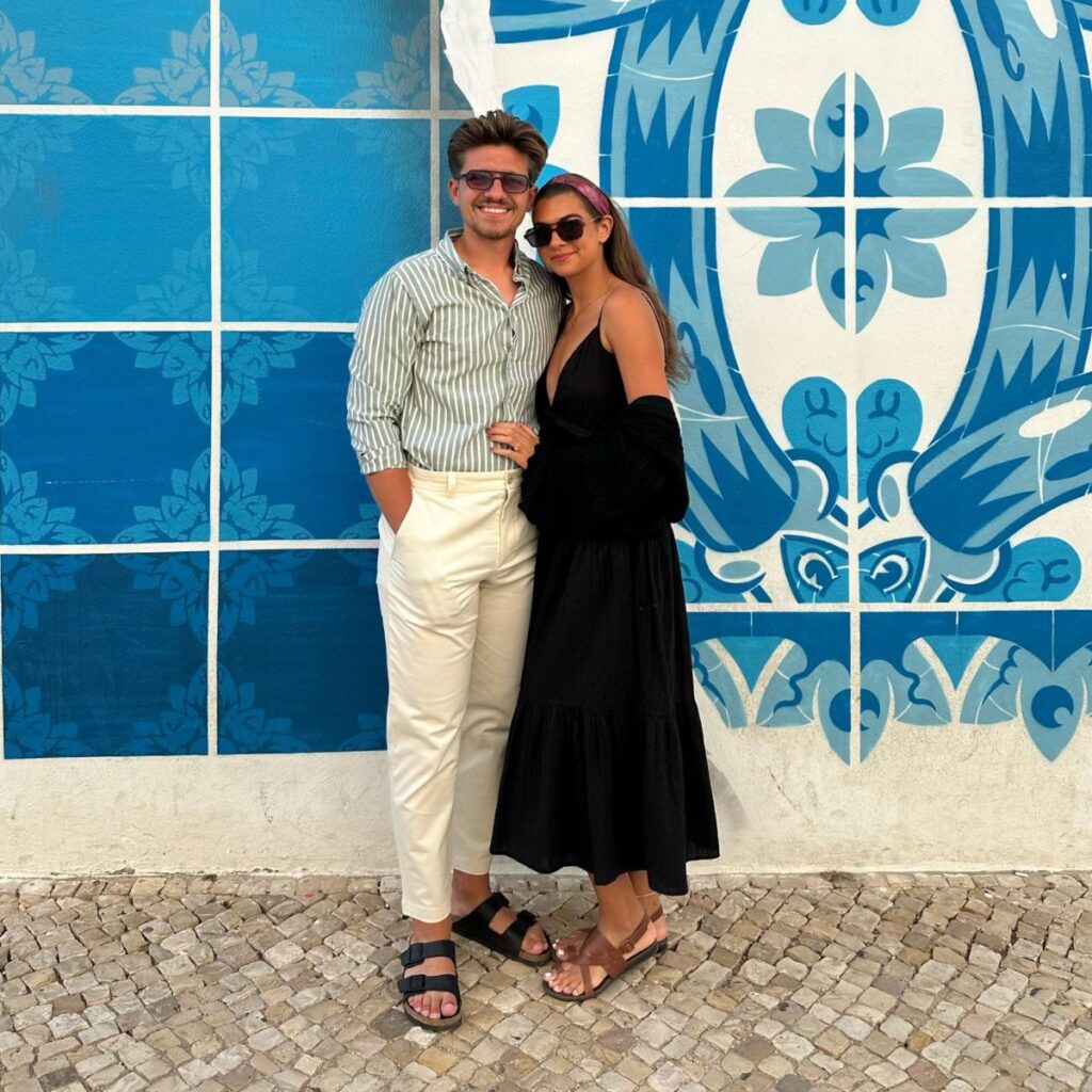 Couple in front of tile blue wall.
